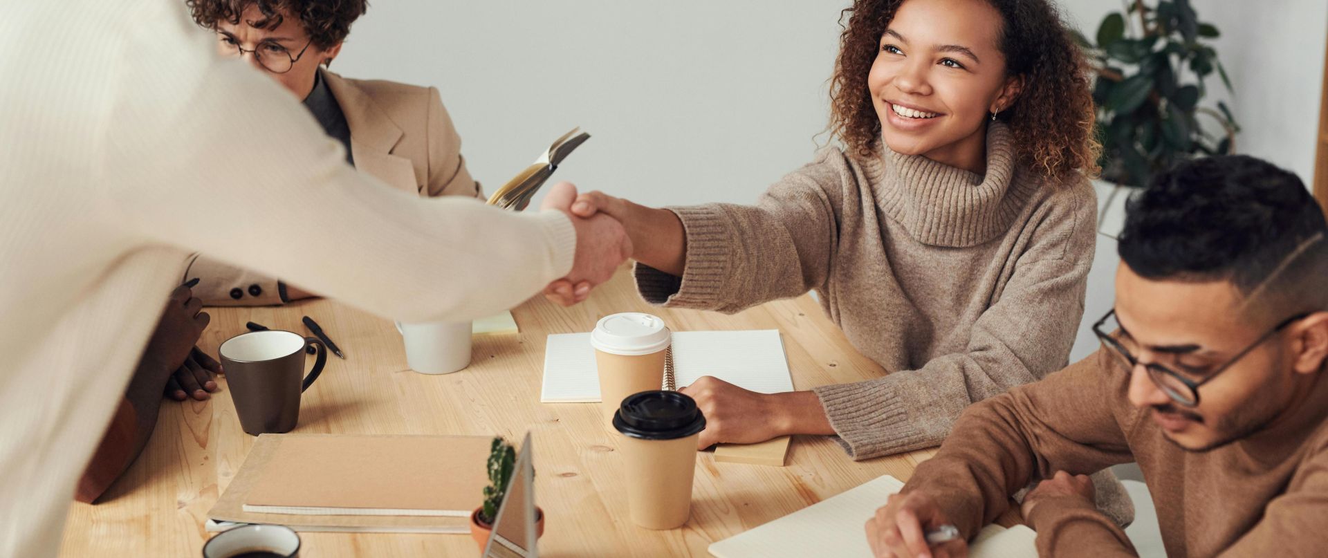 Colleagues in a positive meeting, exchanging a handshake while discussing projects.